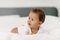 The kid lies in a snow-white bed, laughs and plays with a rattle. Royalty Free Stock Photo