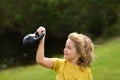 Kid lifting the kettlebell in park outside. Child boy pumping up biceps muscles with kettlebell. Fitness kids with Royalty Free Stock Photo