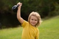 Kid lifting the kettlebell in park outside. Sport child workout. Child exercising with kettlebell. Sporty child with Royalty Free Stock Photo