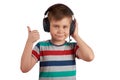 Kid listens to his favorite music on headphones and shows thumb up , isolated on white background. Leisure, music and Royalty Free Stock Photo