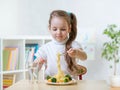 Kid little girl eats vegetarian food at home or kindergarten