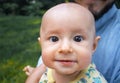 Kid looking at the camera and smiling close-up. Dad holds his baby son in his arms outdoors Royalty Free Stock Photo