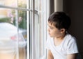 Kid looking at the midge climbing up outside of double glazed window. Young boy sitting next to window looking out at insect with Royalty Free Stock Photo