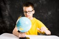 Kid looking at small globe on desk