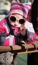 Kid looks at camera on playground, little girl plays with soft toy outdoors in spring. Portrait of funny child in sunglasses