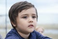 The kid lost in thought looking out withblurry sea view background, Side view portrait of  little boy deep in thoughts. Close up t Royalty Free Stock Photo