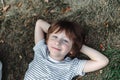 Kid lying on his back in the grass in park. Boy chilling on green lawn. Child relaxing outside, resting his head on Royalty Free Stock Photo