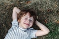 Kid lying on his back in the grass in park. Boy chilling on green lawn. Child relaxing outside, resting his head on Royalty Free Stock Photo