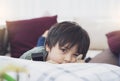 Kid lying on sofa looking at camera with thinking face, Cute boy laying down on couch holding remote, Child watching TV relaxing Royalty Free Stock Photo