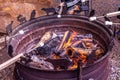 Kid make roasted marshmallows on a fire in a fire pit made of large truck wheel.