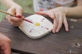 The kid makes a craft - paints a wooden base with brush and colors