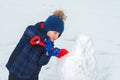 Kid makes a snowman with a shovel and plays in the snow Royalty Free Stock Photo