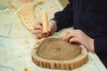 Kid makes wooden clock in the workshop. Boy burn out numbers with soldering iron on wooden disc Royalty Free Stock Photo