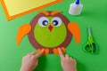 Kid is making a owl with color paper, glue and scissors