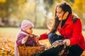 Kid and mother sit with apples basket outdoors in autumnal park Royalty Free Stock Photo