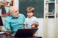Kid with old teacher learning in class on background of blackboard. Old and Young. Teacher is skilled leader. Student Royalty Free Stock Photo