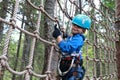 Kid overcoming mesh obstacle in forest adventure park Royalty Free Stock Photo