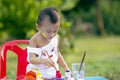 Girl with dirty hands and fingers, using paintbrush painting on paper and her Tank top