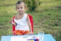 Girl with dirty hands and fingers, using paintbrush painting on paper and her Tank top