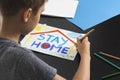 Kid painting pictures with words Stay at home. Social media campaign for coronavirus prevention
