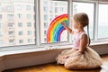 Kid painting rainbow during Covid-19 quarantine at home. Girl near window. Stay at home Social media campaign for coronavirus Royalty Free Stock Photo