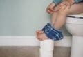 Kid pinching fingers to help with stomach ache, Child boy having with bad tummy problem and diarrhea,Low view of  legs hanging Royalty Free Stock Photo