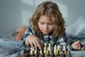 Kid play chess at home. Child think about chess game. Intelligent, smart and clever school kid pupil. Games for brain Royalty Free Stock Photo