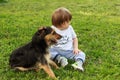 Kid play with cute little puppy. Down syndrome boy and dog playing in sunny summer garden.  Family and pets on park lawn. Kid and Royalty Free Stock Photo