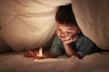 Kid play internet online game, under duvet. Royalty Free Stock Photo