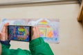 Kid playing Augmented Reality popup paintings of a color filled Taj Mahal via mobile. AR and VR Royalty Free Stock Photo