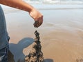 Kid playing on the black sand beach creating and building sandcastle in summertime