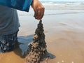 Kid playing on the black sand beach creating and building sandcastle in summertime