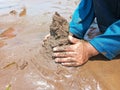 Kid playing on the black sand beach creating and building sandcastle in summertime