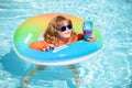 Kid playing in blue water. Happy child playing with colorful swim ring in swimming pool on summer. Children play in