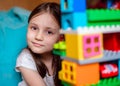 Kid is playing with Colorful lego bloks in her room. Close-up.