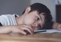 Kid playing colour pencil sitting alone and looking down with bored face, Preschool child boy laying head down on table looking