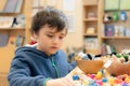 Kid playing colourful wooden blocks  and soft toy in play room,Young boy playing alone in school library,Educational toys for Royalty Free Stock Photo