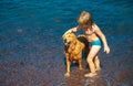 Kid playing with dog on beach. Little boy playing with dog in water. Royalty Free Stock Photo