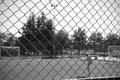 Kid playing football on a playground in a park surrounded by a wire mesh. in black and white for greater drama. alone on the footb