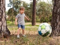 Kid playing football soccer at grass city park field running and kicking the ball excited in childhood sport passion and Royalty Free Stock Photo