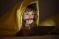 Kid playing game on tablet in bed at night. Kids with social media. Child lying in bed playing a tablet in dark room Royalty Free Stock Photo