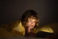 Kid playing game on tablet in bed at night. Kids with social media. Child lying in bed playing a tablet in dark room Royalty Free Stock Photo