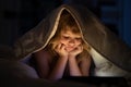 Kid playing game on tablet in bed at night. Kids with social media. Child lying in bed playing a tablet in dark room Royalty Free Stock Photo
