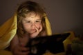 Kid playing game on tablet in bed at night. Kids with social media. Child lying in bed playing a tablet in dark room Royalty Free Stock Photo