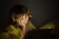Kid playing game on tablet in bed at night. Kids with social media. Child lying in bed playing a tablet in dark room Royalty Free Stock Photo