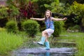 Kid playing out in the rain. Children with umbrella and rain boots play outdoors in heavy rain. Little boy jumping in muddy puddle Royalty Free Stock Photo