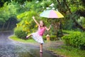 Kid with umbrella playing in summer rain.