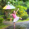 Kid with umbrella playing in summer rain.