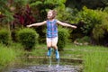 Kid playing out in the rain. Children with umbrella and rain boots play outdoors in heavy rain. Little boy jumping in muddy puddle Royalty Free Stock Photo