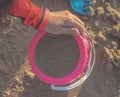 Kid playing with pink plastic bucket full of sand for kid summer vacation toy concept Royalty Free Stock Photo